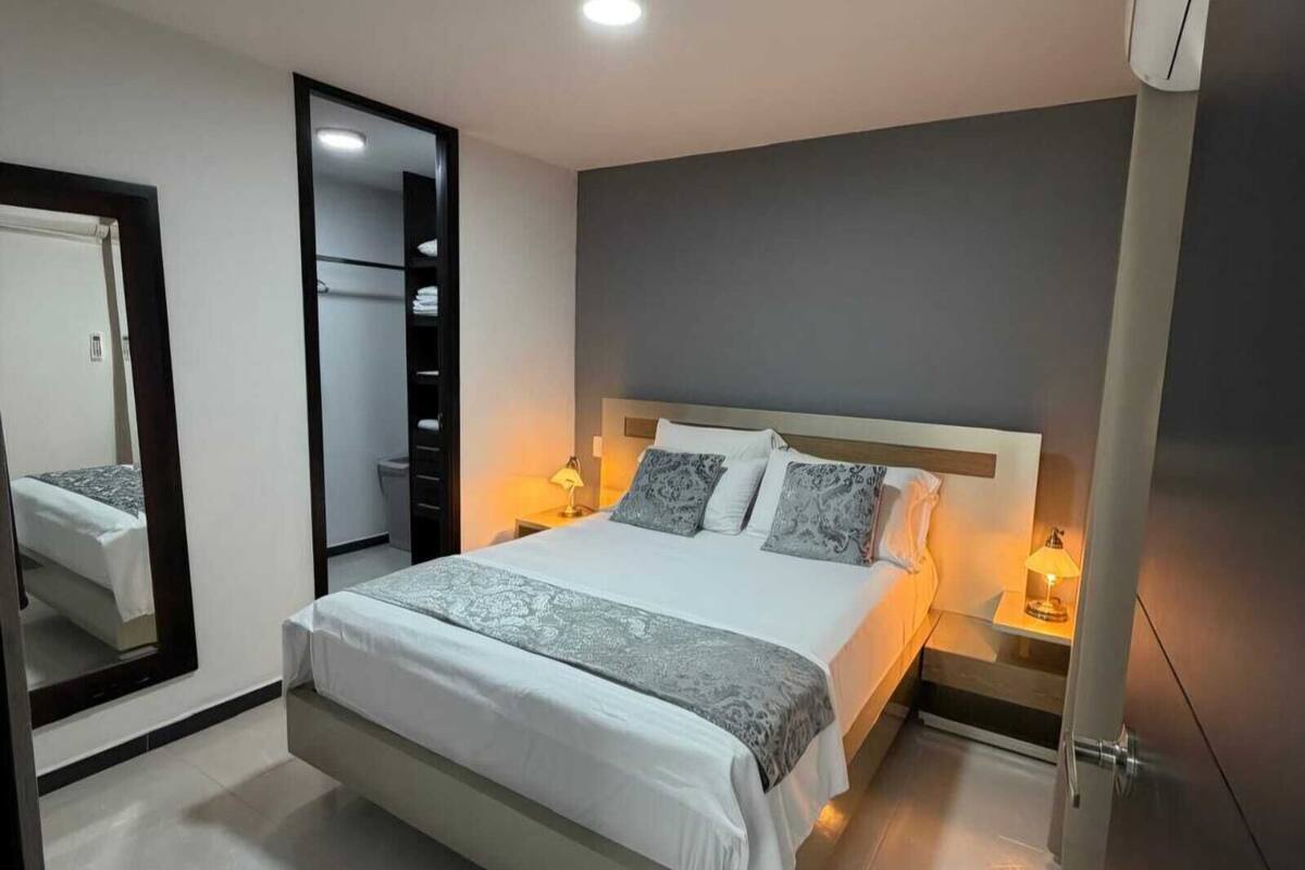 Une chambre moderne avec un grand lit, des lampes de chevet, un miroir et une armoire.