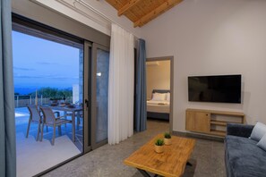 A modern living room with a sofa, a coffee table, a TV, and a balcony with a dining area. - Ionian Harmony Villa 4 | Private Pool & Sea View (Tsoukalades)
