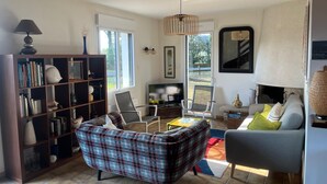 A living room with a sofa, chairs, a bookshelf, a fireplace, and a TV. - House in Penestin, located 350 m from the beach (Penestin)