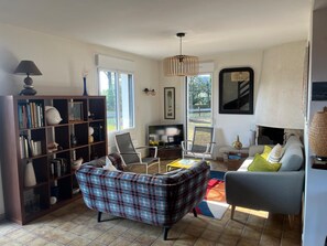 A living room with a sofa, chairs, a bookshelf, a fireplace, and a TV. - House in Penestin, located 350 m from the beach (Penestin)