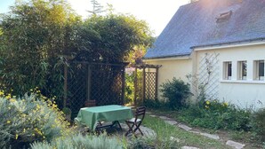 A garden with a table and chairs, a pergola, and a house with a sloped roof. - House in Penestin, located 350 m from the beach (Penestin)