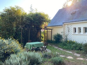A garden with a table and chairs, a pergola, and a house with a sloped roof. - House in Penestin, located 350 m from the beach (Penestin)