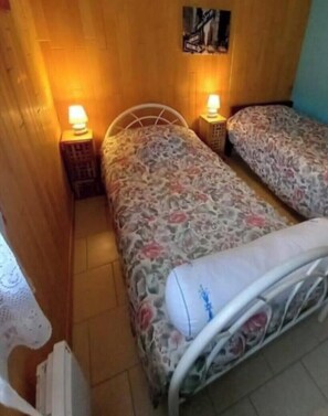Ein kleines Zimmer mit zwei Betten, Holzwänden und zwei Nachttischlampen.