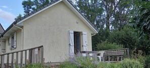 Ein beige gefärbtes Gebäude mit Holzzaun, einer Bank und üppiger Bepflanzung.