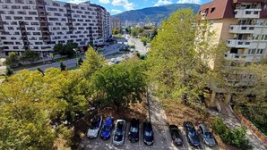Un parcheggio con diverse auto, circondato da alberi ed edifici.