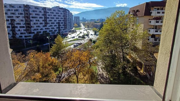 Una vista di uno skyline urbano con edifici moderni, una strada e una montagna all'orizzonte.