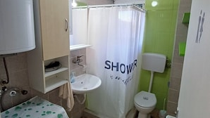 Un bagno con tenda doccia, lavandino, WC e un tappetino verde sul pavimento.
