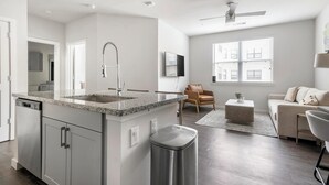 Una cucina moderna con piani in granito, lavello in acciaio inossidabile e pattumiera integrata.