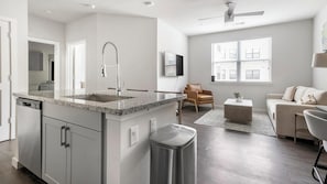 Eine moderne Küche mit Granit-Arbeitsplatten, einer Edelstahl-Spüle und einem integrierten Mülleimer.