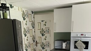 A kitchen with a refrigerator, oven, microwave, and cabinets. - Quiet apartment very close to Fontenay Abbey (Marmagne)