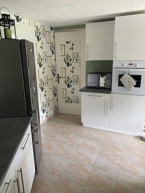 Una cocina equipada con refrigerador, horno, microondas y armarios.