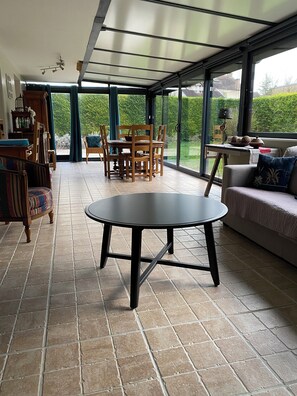 Une vĂ©randa Ă©quipĂ©e dâune table Ă manger, de chaises et dâun canapĂ©.