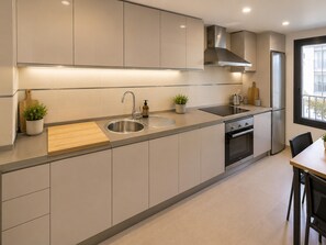 Eine moderne Küche mit Spüle aus Edelstahl, einem eingebauten Backofen und einem Schneidebrett aus Holz.