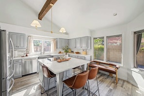 A spacious kitchen with a central island, grey cabinets, and a wooden bench. - NEW| Royal Palms Retreat | Pool, Spa & Pool Table (Tempe)