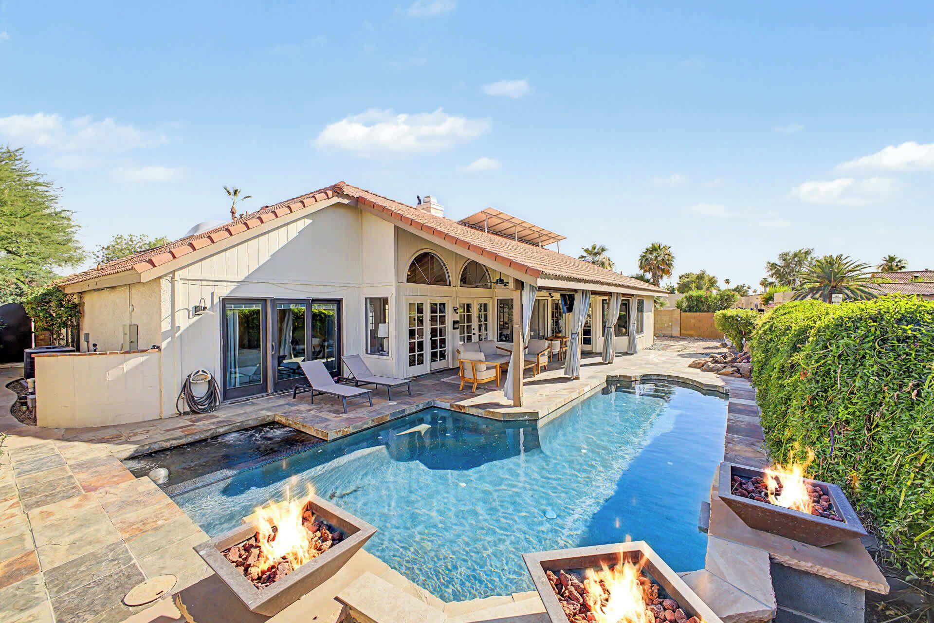A house with a swimming pool, outdoor seating, and a fire pit area.