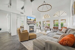 A spacious living room with a fireplace, leather chairs, a sofa, and large windows. - NEW| Royal Palms Retreat | Pool, Spa & Pool Table (Tempe)