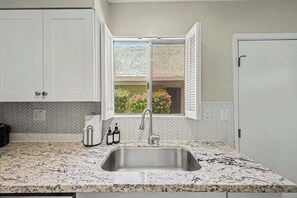 A kitchen with a herringbone tile backsplash, a stainless steel sink, and white cabinets. - NEW|Camelback 352|Resort-Style Stay Near Old Town (Scottsdale)