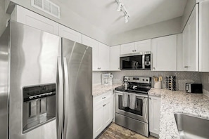 A modern kitchen with stainless steel appliances, white cabinetry, and a herringbone-patterned backsplash. - NEW|Camelback 352|Resort-Style Stay Near Old Town (Scottsdale)
