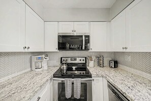 A kitchen with white cabinets, a microwave, a stove, a coffee maker, and a toaster. - NEW|Camelback 352|Resort-Style Stay Near Old Town (Scottsdale)