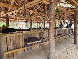 A wooden bar area with hanging seats and a thatched roof. - PILI BEACH RESORT AGMANIC (Santa Fe)