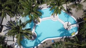 An aerial view of a swimming pool surrounded by palm trees, with a circular water feature and a small island in the center. - PILI BEACH RESORT AGMANIC (Santa Fe)