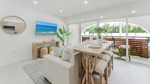 Uma sala de estar moderna com sofá, mesa de jantar e grandes janelas.