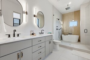 Moderni kylpyhuone, jossa on suuri peili, kaksi pesuallasta, kylpyamme ja wc.
