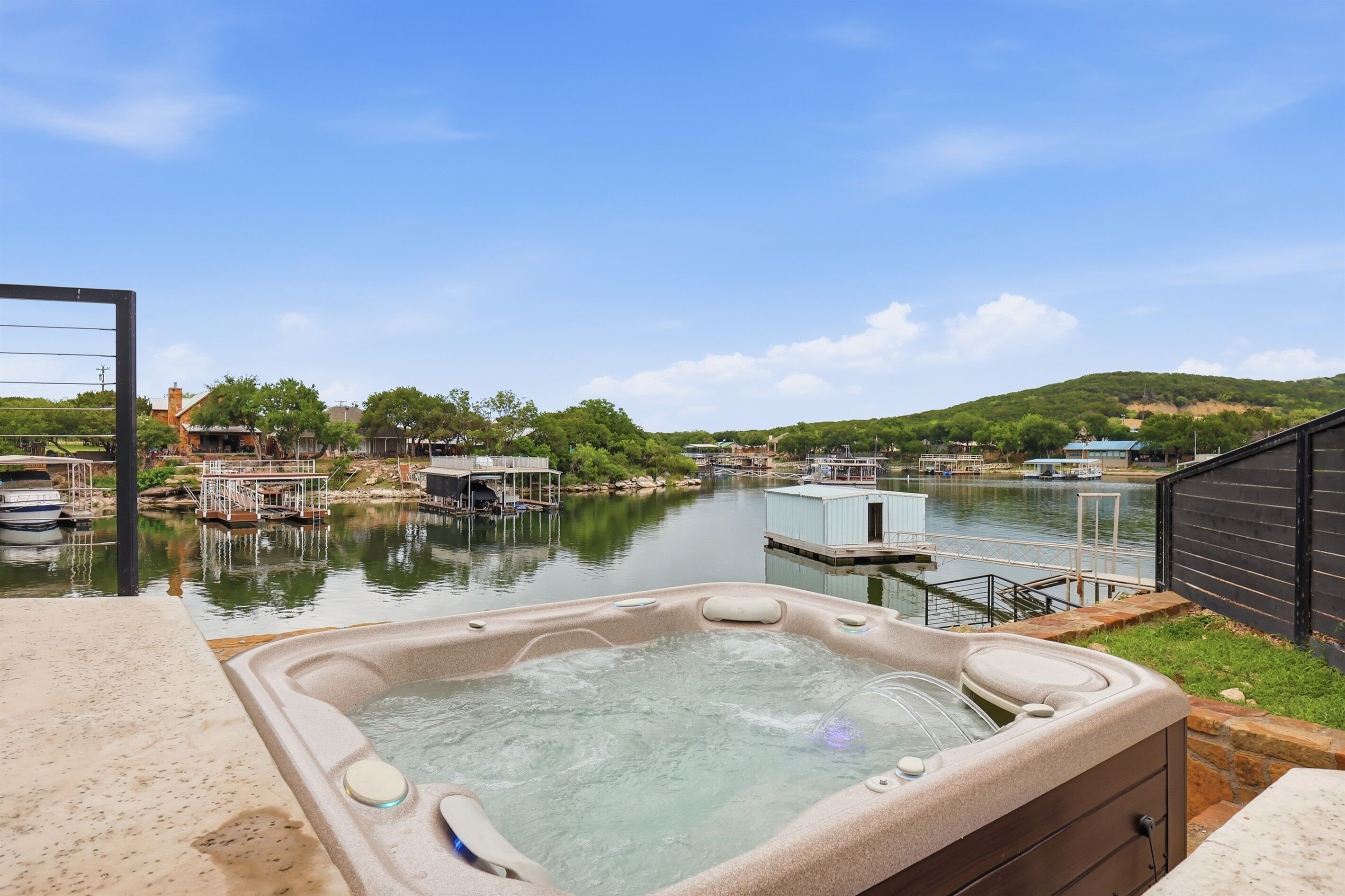 A hot tub with a clear view of a river, docked boats, and a hilly landscape.