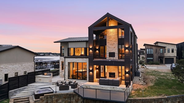 A modern two-story house with a stone facade, large windows, and outdoor seating.