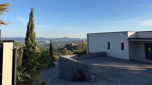 Um edifício moderno com parede de pedra e vista para uma cidade e montanhas ao longe.
