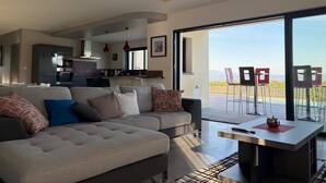 Uma sala de estar moderna com um sofá, uma mesa de jantar e vista para o exterior.