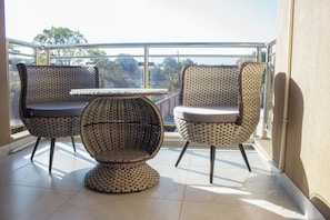 A balcony with wicker furniture, including two chairs and a round table. - Monga's Apartments (Ndola)