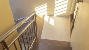 Eine Treppe mit Metallgeländern und Holzdielen, die zu einer Zwischenebene mit Geländer und einem an der Wand befestigten Lichtschalter führt.