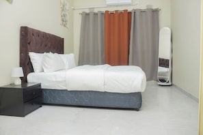 A neatly arranged bedroom with a bed, bedside table, and a mirror.