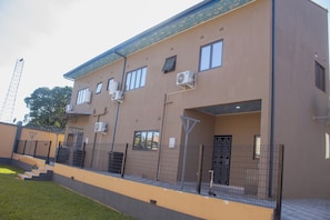 A multi-story building with air conditioning units, a gated entrance, and a staircase leading to the upper floors.