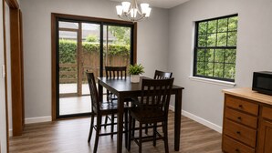 Un coin repas comprenant une table, des chaises, un lustre, une plante en pot, une fenêtre et un meuble en bois.