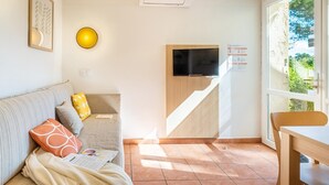 Uma sala de estar moderna com sofá, televisão, mesa de jantar e escada para um andar superior.