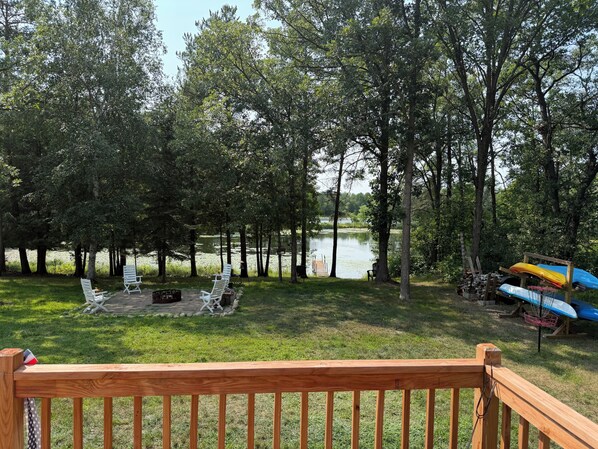 A deck with a view of a lake surrounded by trees, outdoor seating, and kayaks. - Ketcher's Last Resort - 2br cabin on Straight Lake, Osage, MN (Osage)