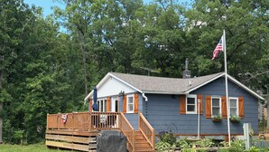 A house with a deck, a flag, and a covered grill.