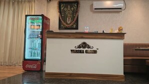 A reception desk with a Coca-Cola refrigerator, a framed religious artifact, and a wall-mounted air conditioner. - Varsha Grand  (Hyderabad)