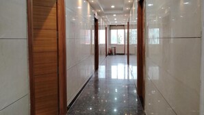 A corridor with a polished floor, wooden doors, and recessed lighting. - Varsha Grand  (Hyderabad)
