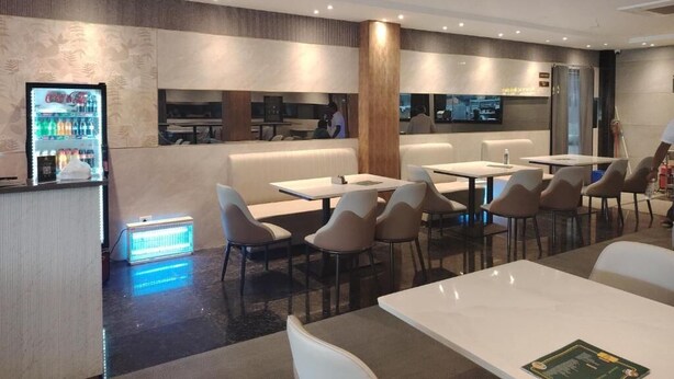 A modern hotel lobby with seating areas, a refreshment bar, and a television screen. - Varsha Grand  (Hyderabad)