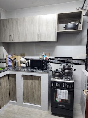 A kitchen with a stove, microwave, and cabinets. - BRIGIT LUXURY APARTMENT  (Kisumu)