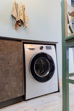 Ein moderner Waschraum mit einer Samsung Waschmaschine, Holzausbau und einem an der Wand befestigten Wäscheständer.