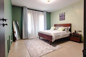 Ein Schlafzimmer mit einem Bett, einem Nachttisch, einem Spiegel, einem Fenster mit Vorhängen und einem Wandbild.