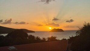 Atardecer sobre el océano con una isla distante, cielo despejado y vista al mar.