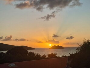 Ein Sonnenuntergang über dem Meer mit einer entfernten Insel, klarem Himmel und Blick auf die See.