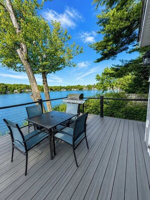 Um terraço com mesa e cadeiras, com vista para um lago.