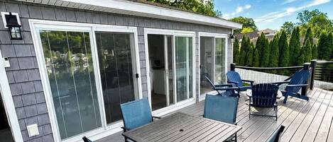 Eine Terrasse mit Tisch und Stühlen, ein überdachter Patio-Bereich und ein Haus mit Glasschiebetüren.