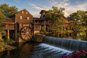 A rustic wooden mill with a water wheel and a restaurant named 'Old Mill Restaurant' adjacent to a river. - Cozy 3BR Cabin with Hot Tub, Pool Table & Arcade (Sevierville)